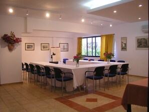 A conference room with a long table, chairs, a whiteboard, and framed pictures on the walls. - Ippokampos Hotel (Hydra)