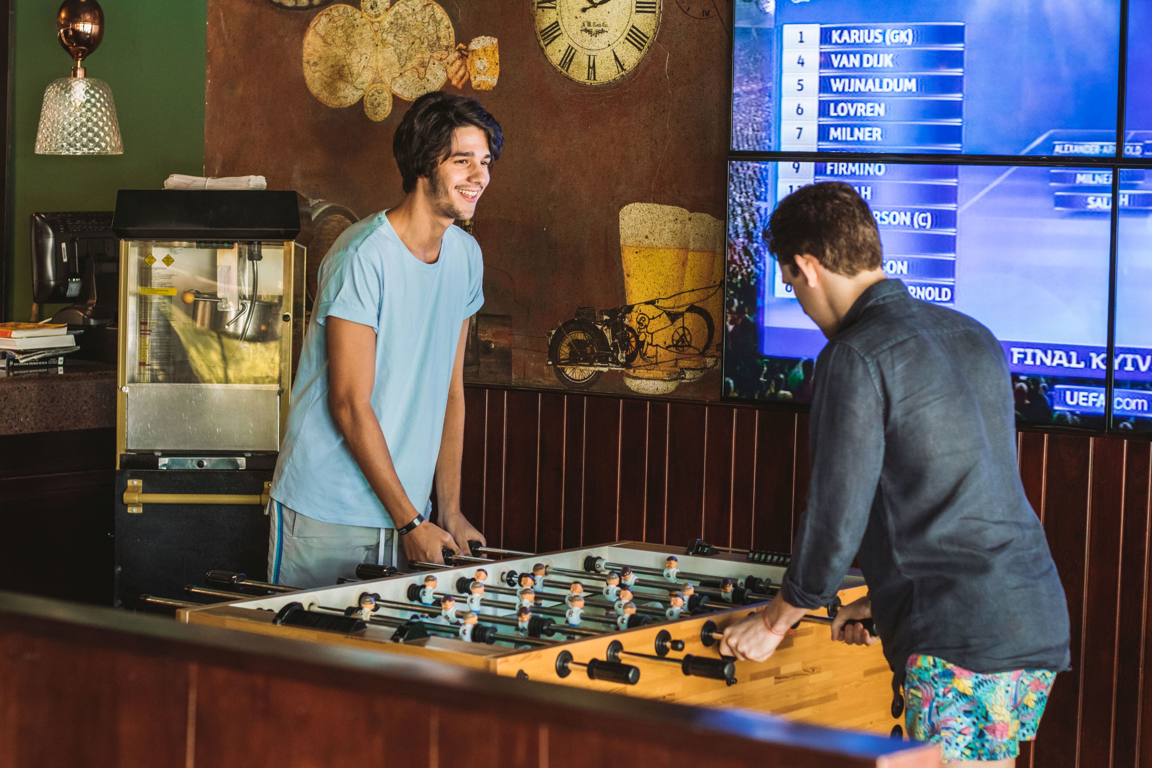 Un área de bar con mesa de fútbol de mesa, máquina de café y cartel de menú.