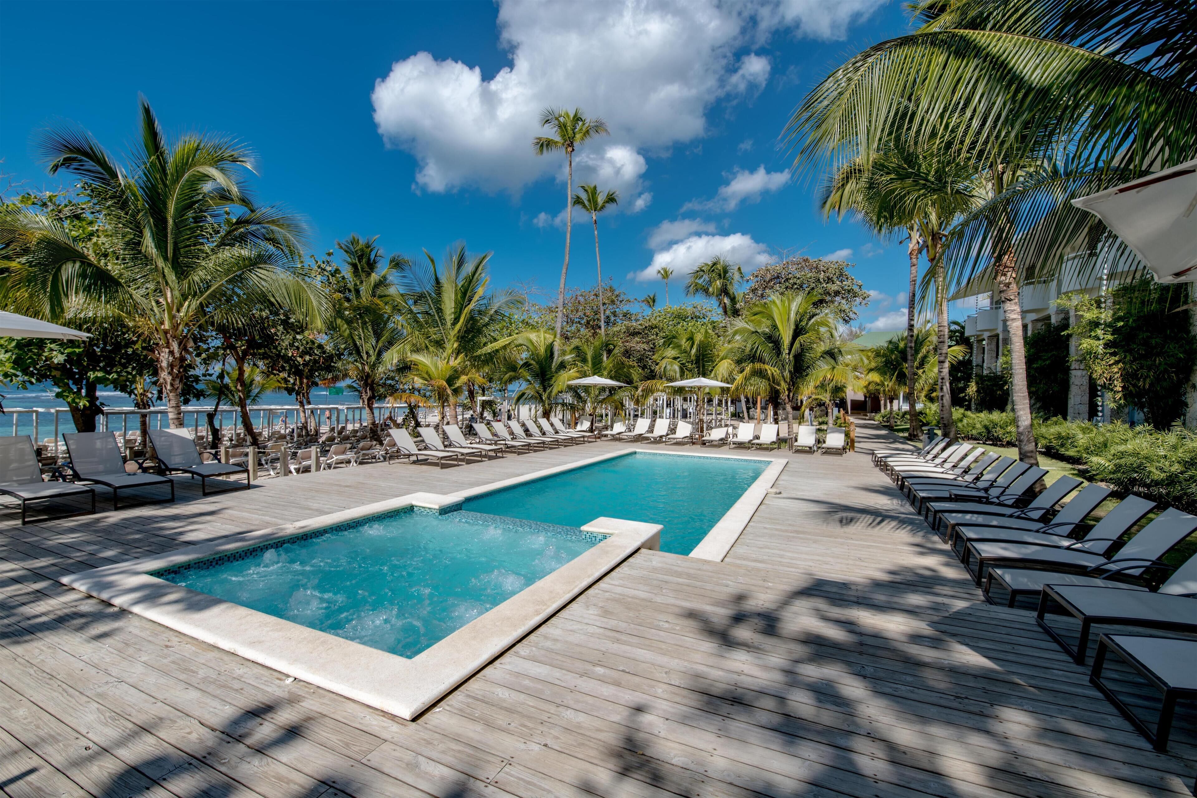 A pool area with lounge chairs and palm trees.