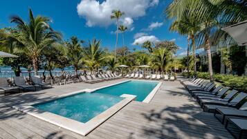 A pool area with lounge chairs and palm trees.