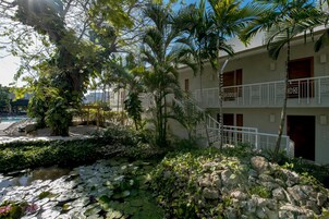 Un hotel con piscina, exuberante vegetación y un camino de piedra.