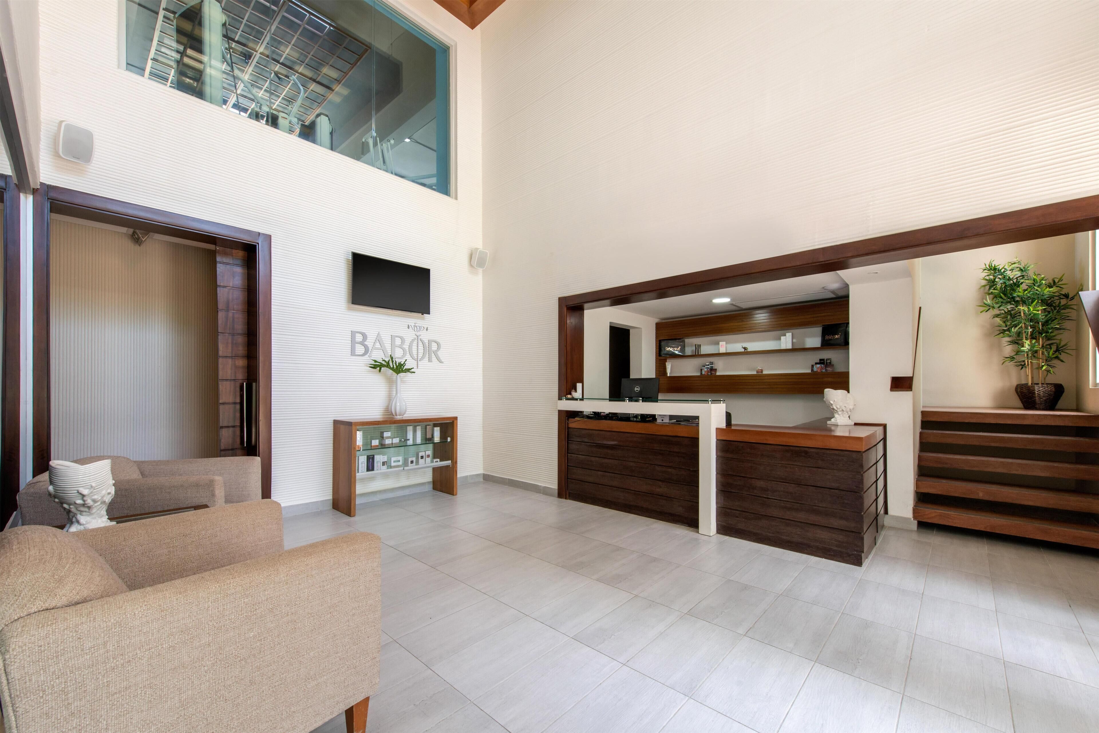 Amplia sala de estar con techo alto, mostrador de recepción y una escalera que conduce a un piso superior.