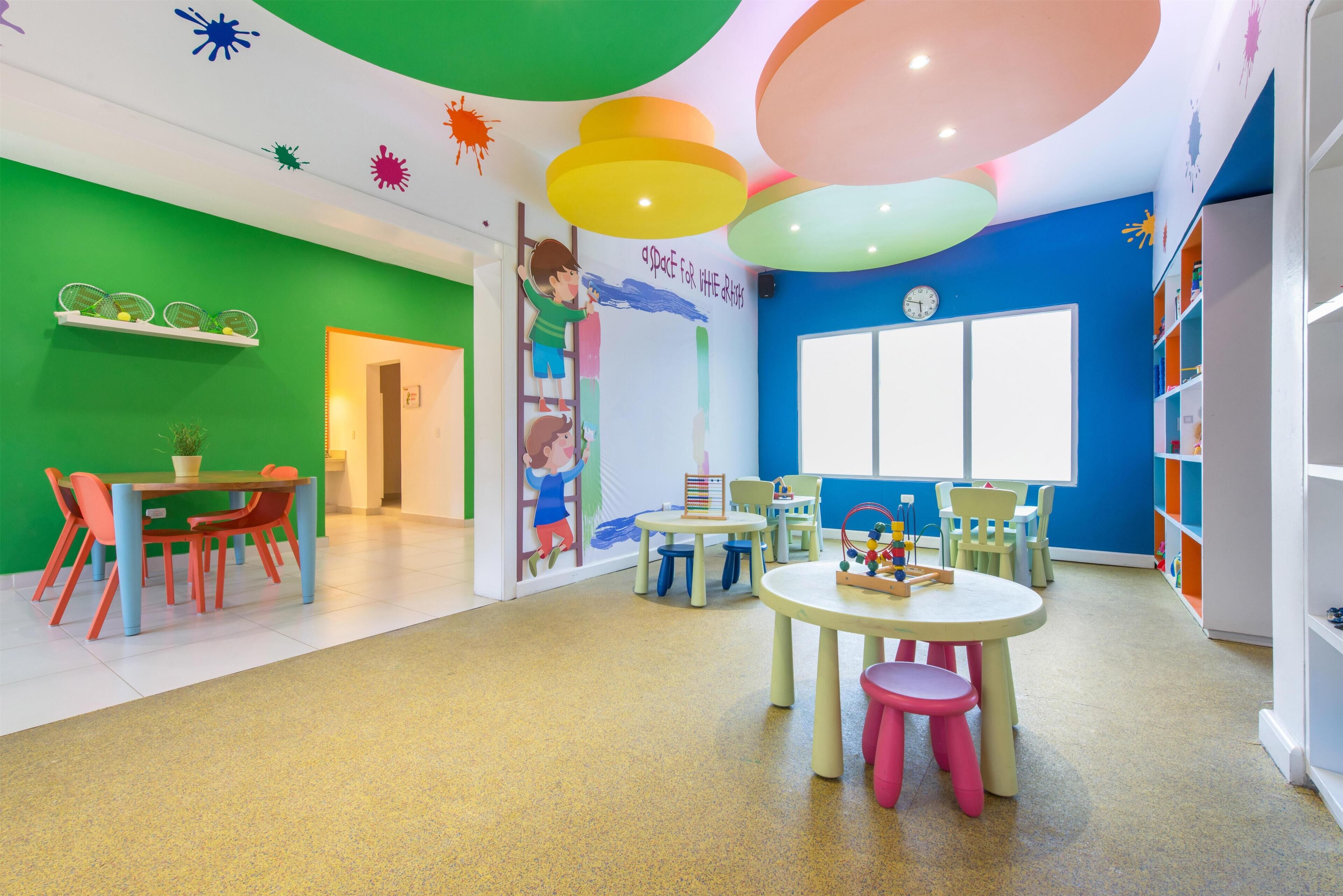 Un salón infantil de colores vivos con mesas, sillas y juguetes educativos.