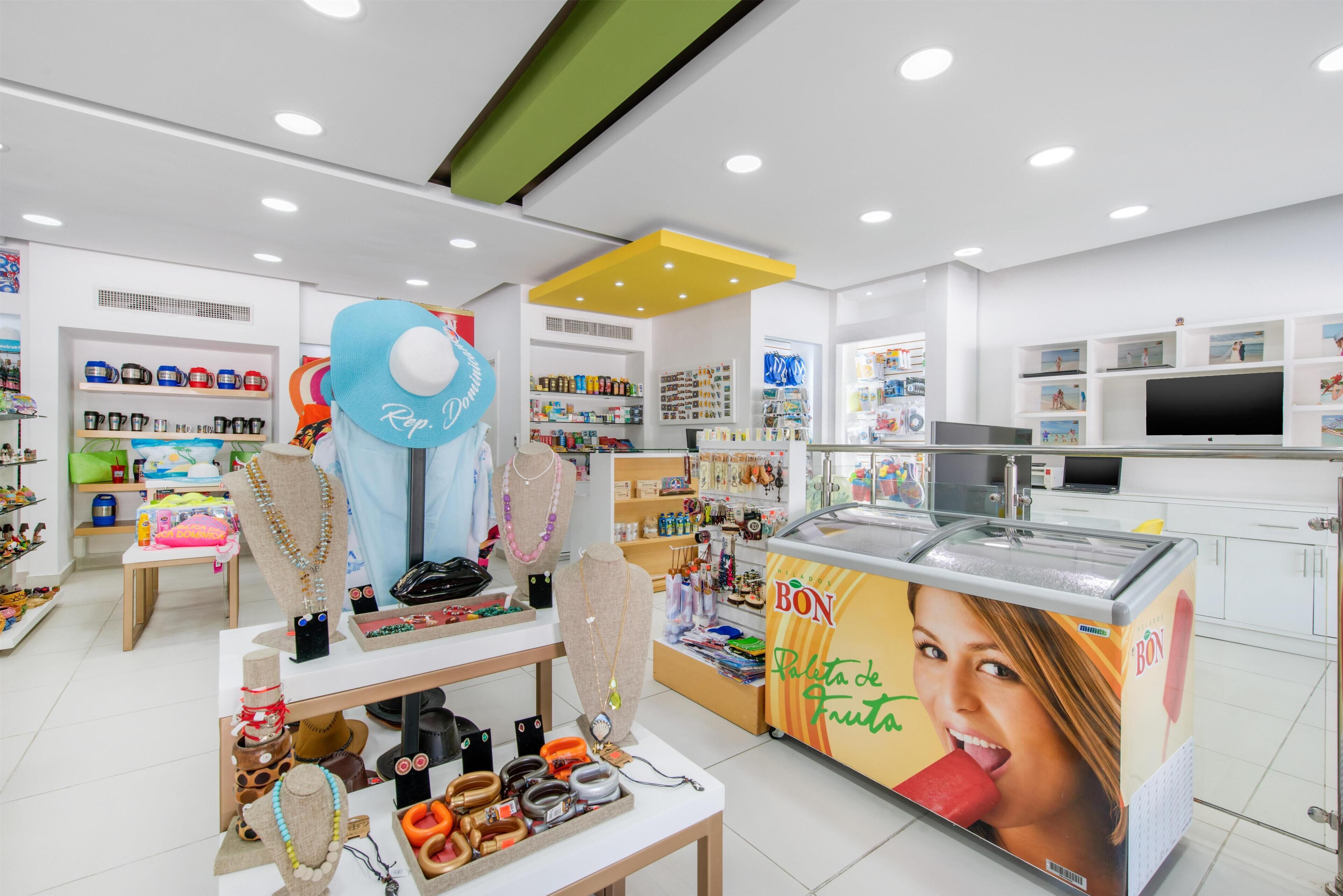 Un magasin bien éclairé où sont exposés divers articles, notamment des bijoux, des en-cas et un grand congélateur.