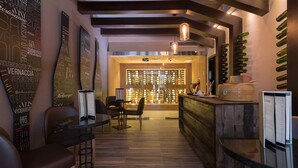 A modern interior with a reception desk, wooden flooring, and a wall with hanging bottles.