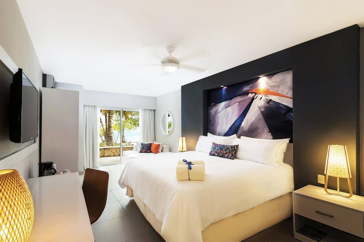 Ein Hotelzimmer mit Bett, Nachttischen, Fernseher, Schreibtisch und Stuhl.