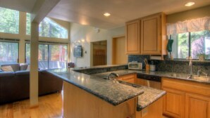 Una cocina moderna con encimeras de granito, armarios de madera y lavavajillas integrado.