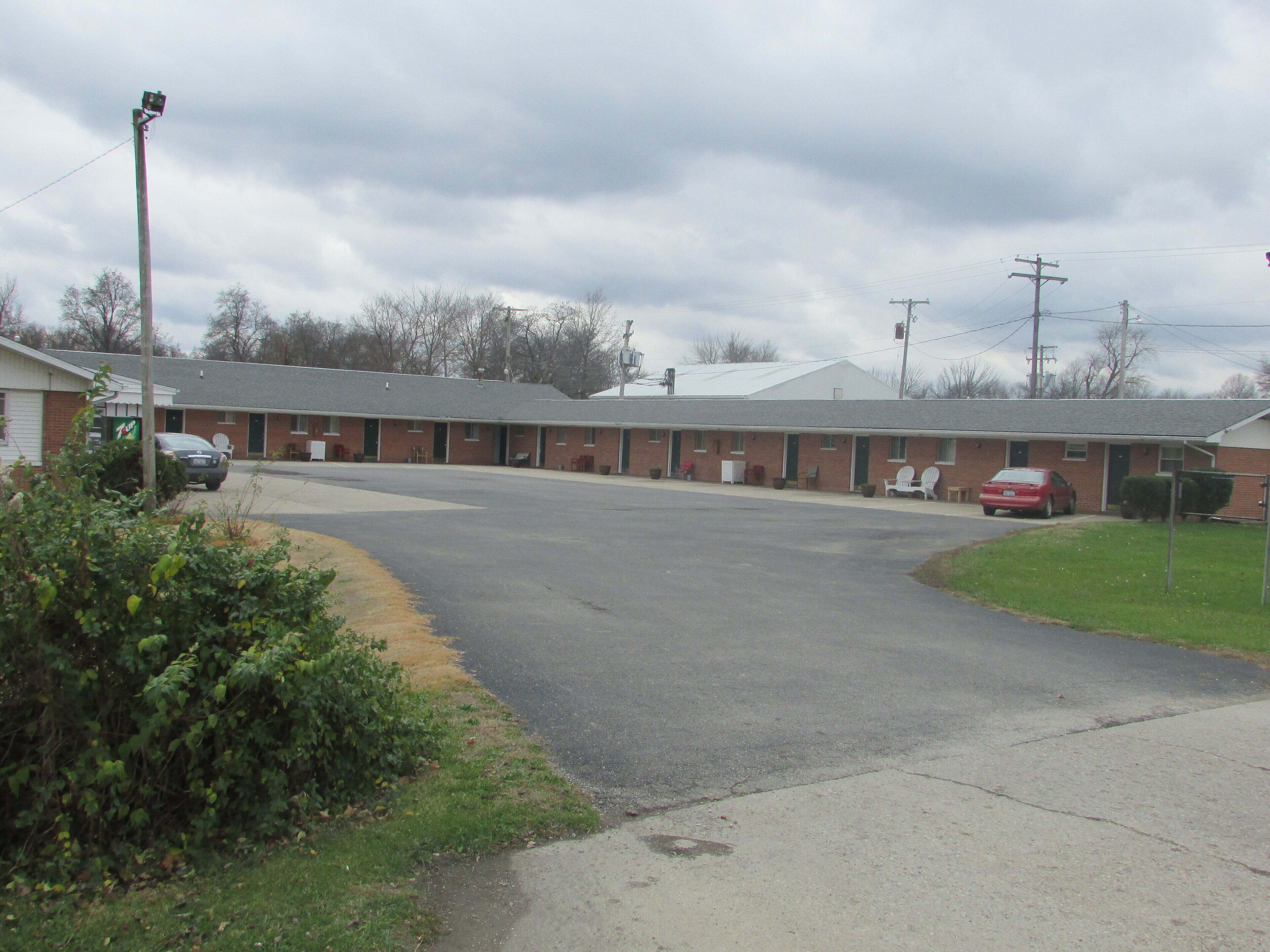 A motel with a central parking area, a row of rooms, and a small lawn.