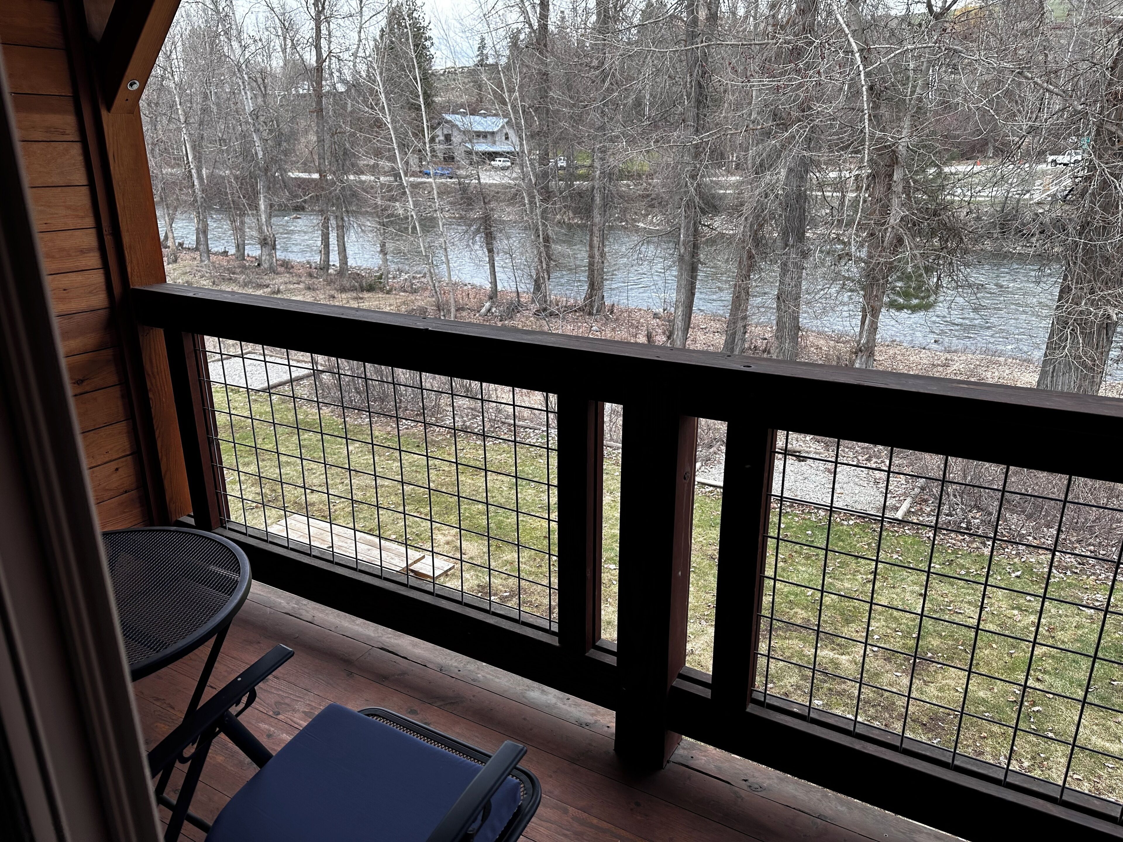 A wooden deck with a metal railing overlooking a body of water and trees.