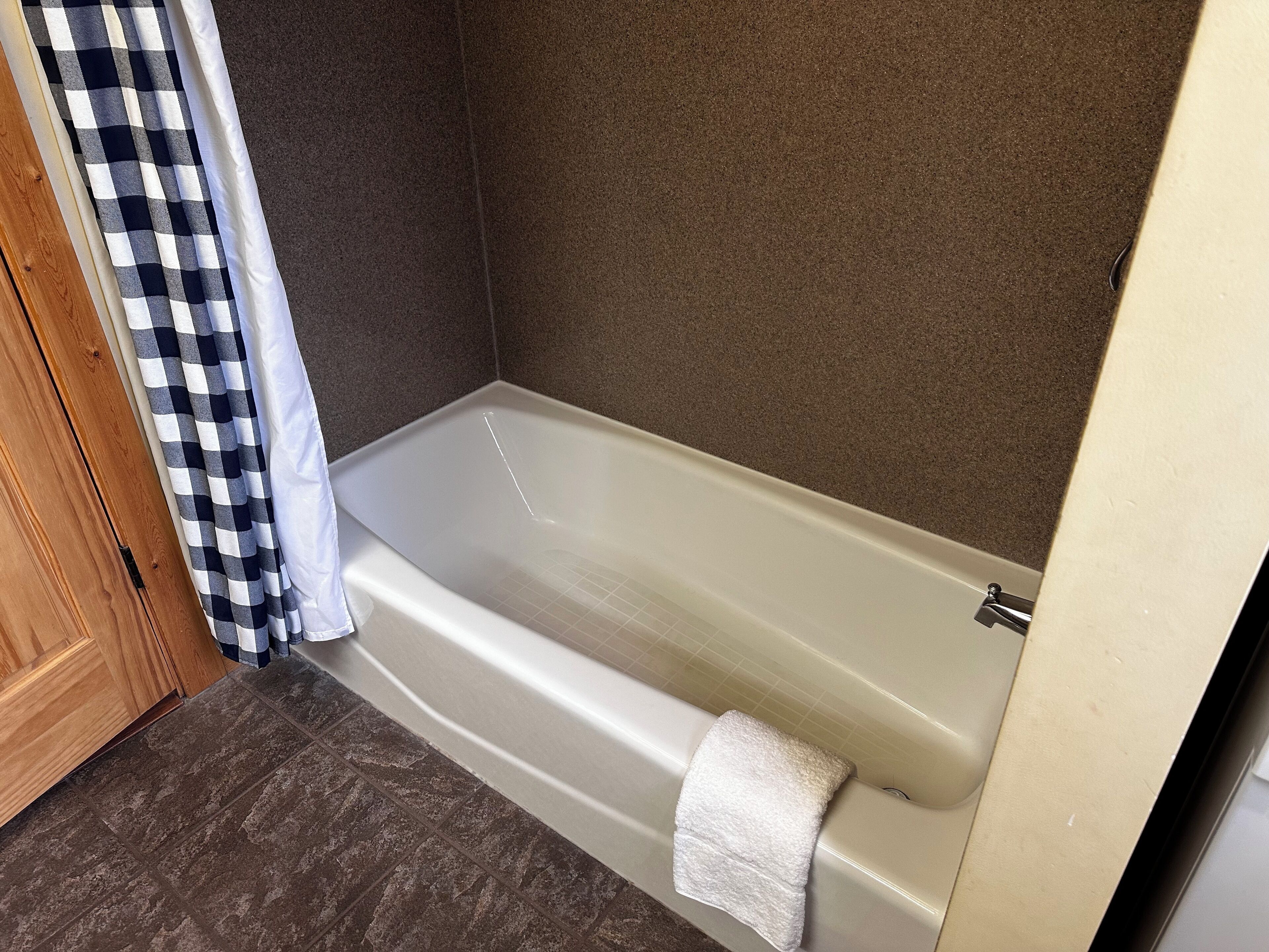 A bathroom with a bathtub, a shower curtain, and a towel.