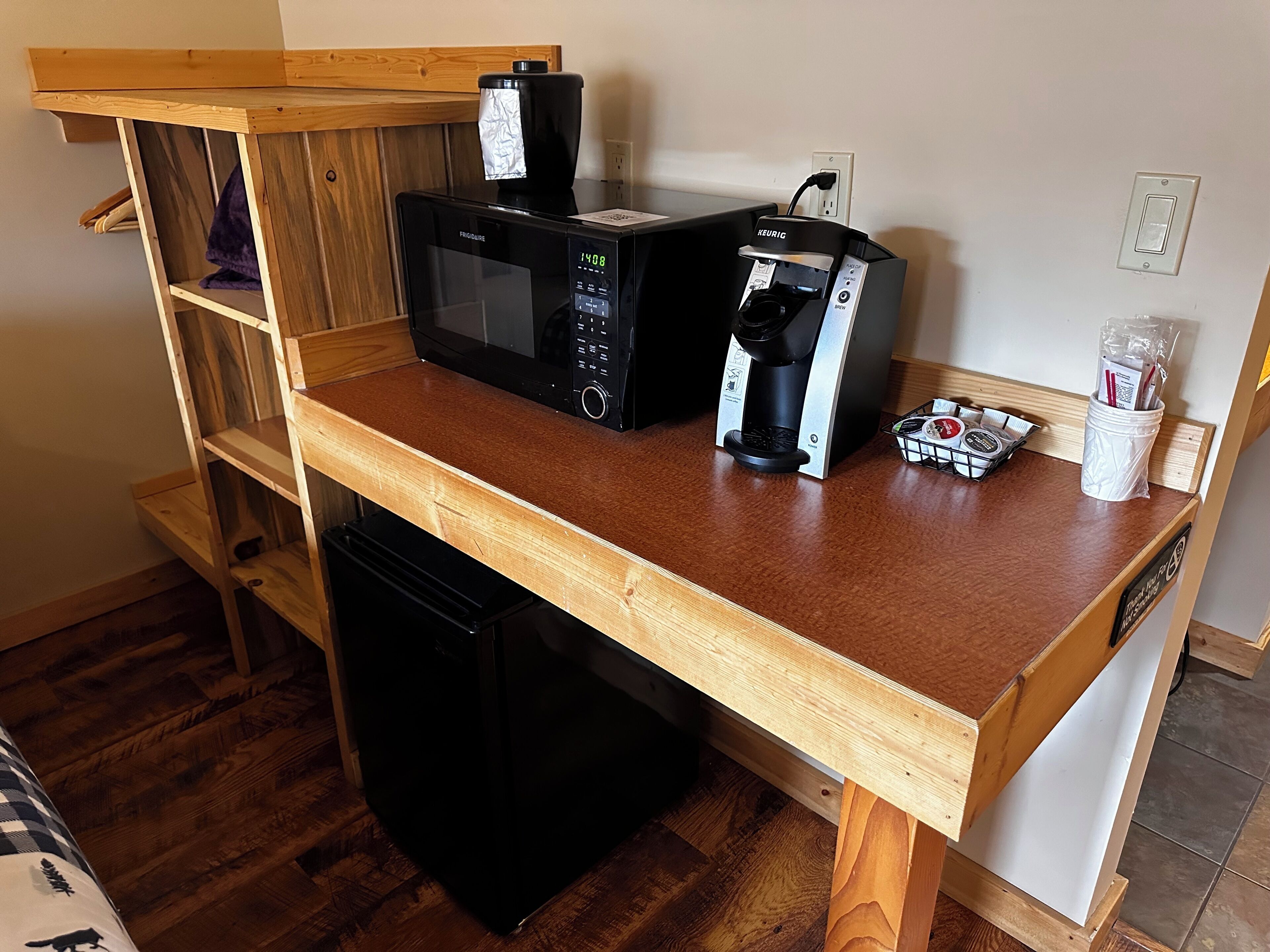 Una kitchenette compacta equipada con microondas, cafetera y un refrigerador pequeño.