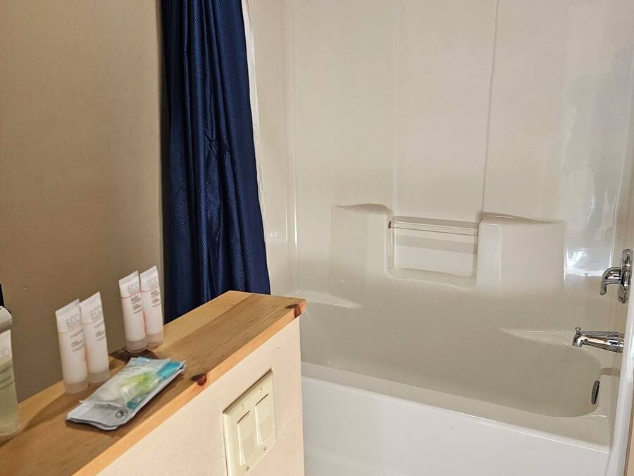 A bathroom with a bathtub, a wooden counter with toiletries, and a blue shower curtain.