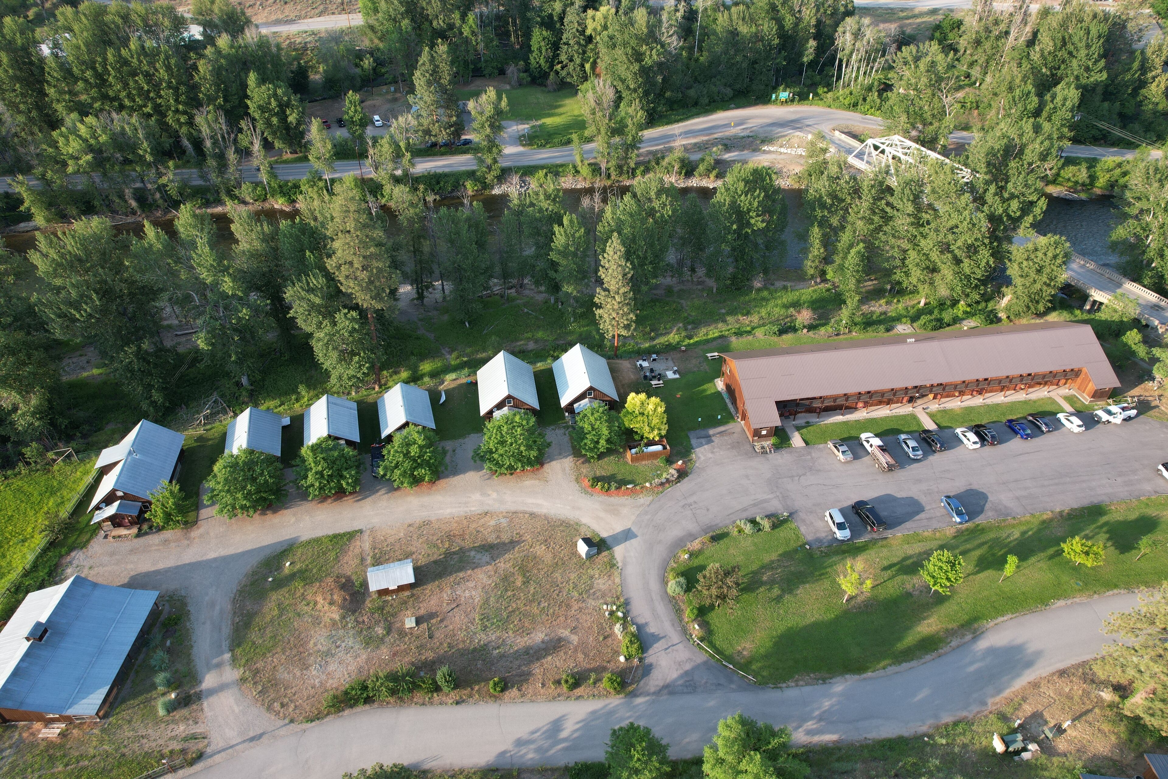 An aerial view of a property with multiple buildings, a parking lot, and surrounding greenery.