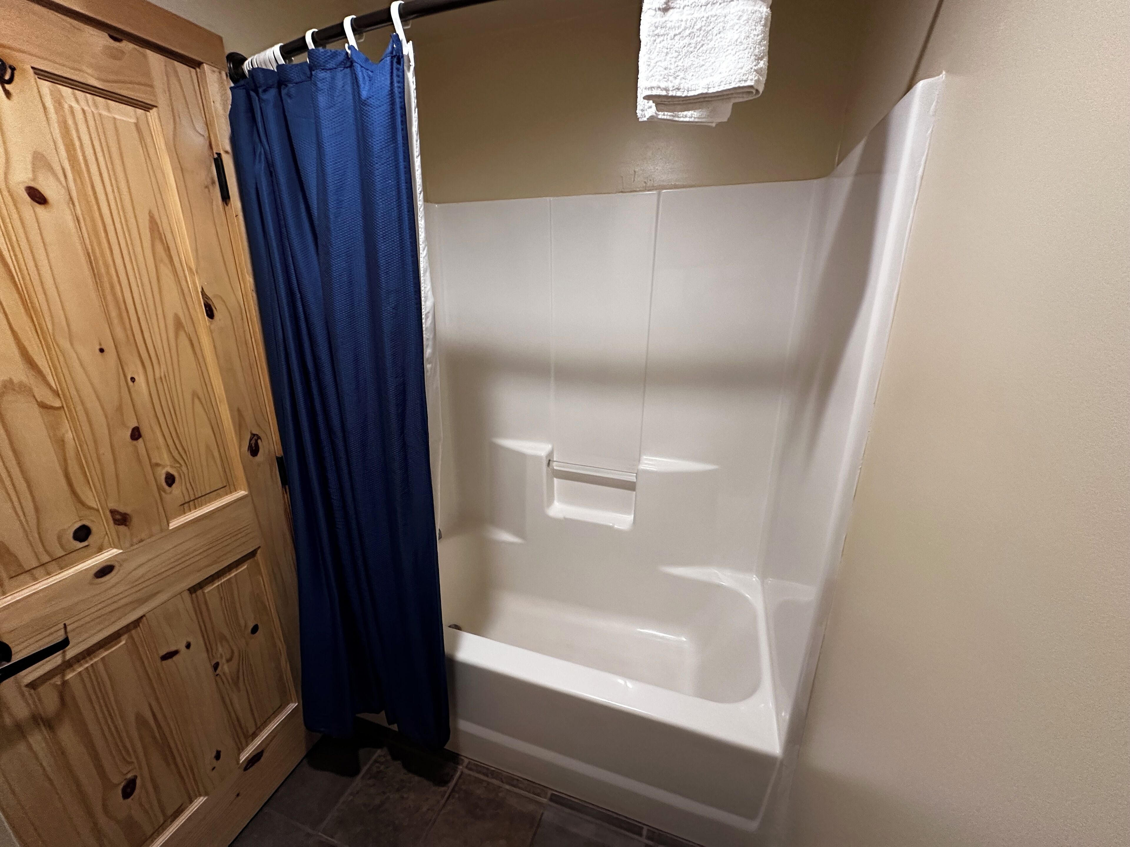 Ein Badezimmer mit einem Holzkabinent, einem blauen Duschvorhang und einer weißen Badewanne.