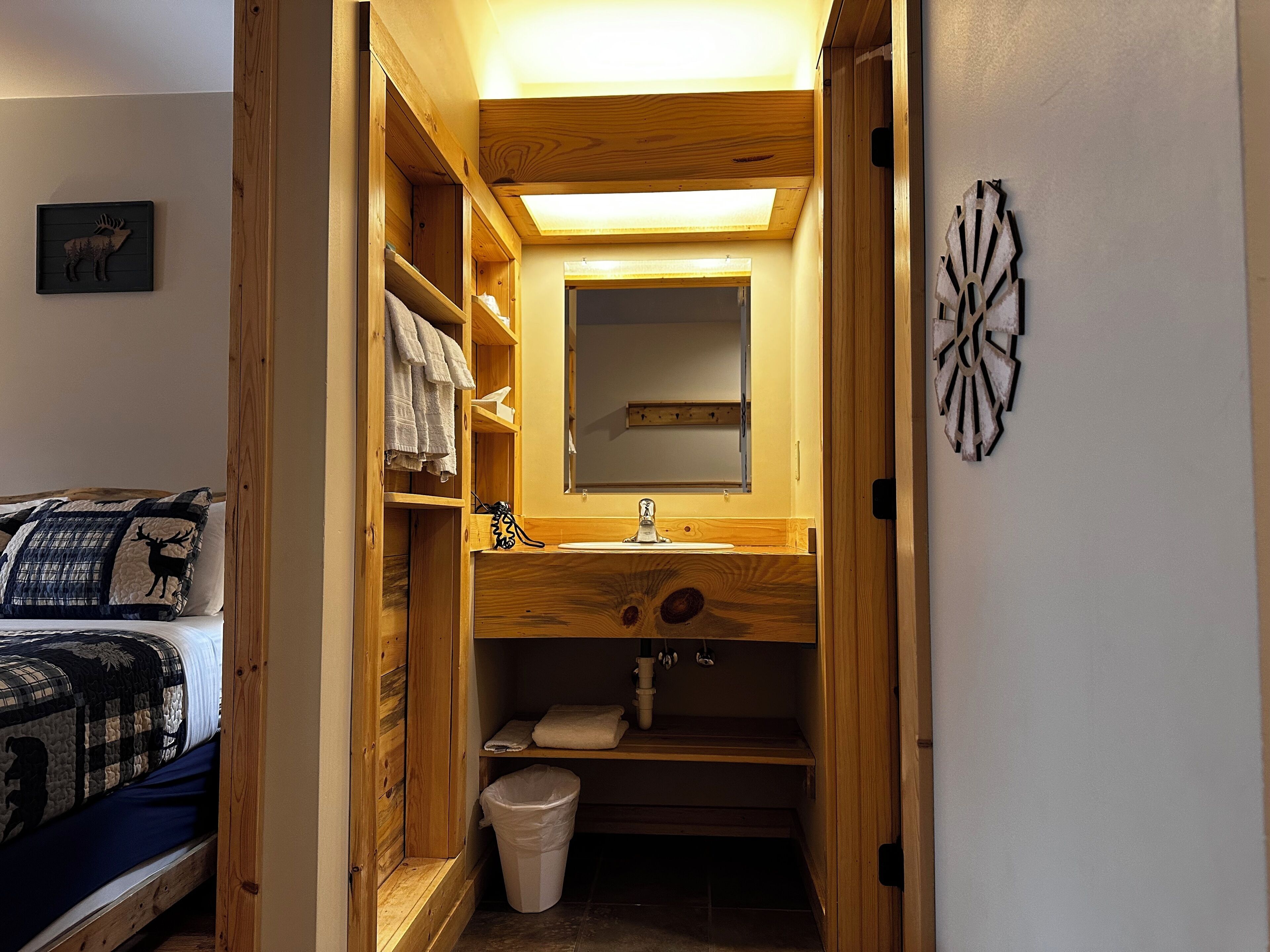 Un baño pequeño con tocador de madera, un espejo y un lavamanos.