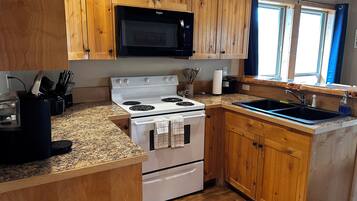 Una cocina con armarios de madera, estufa blanca, microondas y encimera de granito.