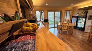A kitchen with wooden cabinets, a fruit basket, a refrigerator, and a dining area with a table and chairs.
