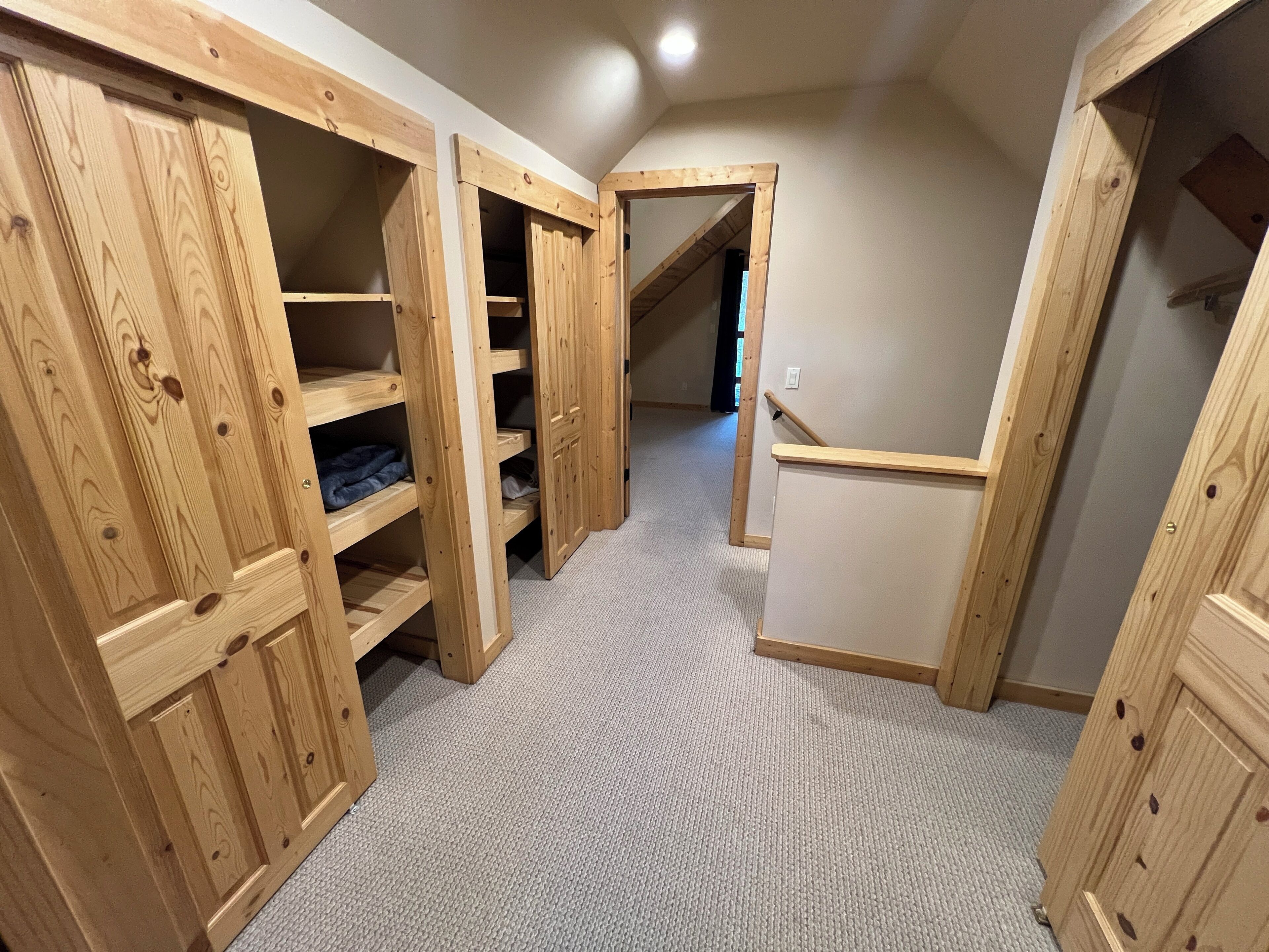 A narrow hallway with wooden shelving units and a carpeted floor.