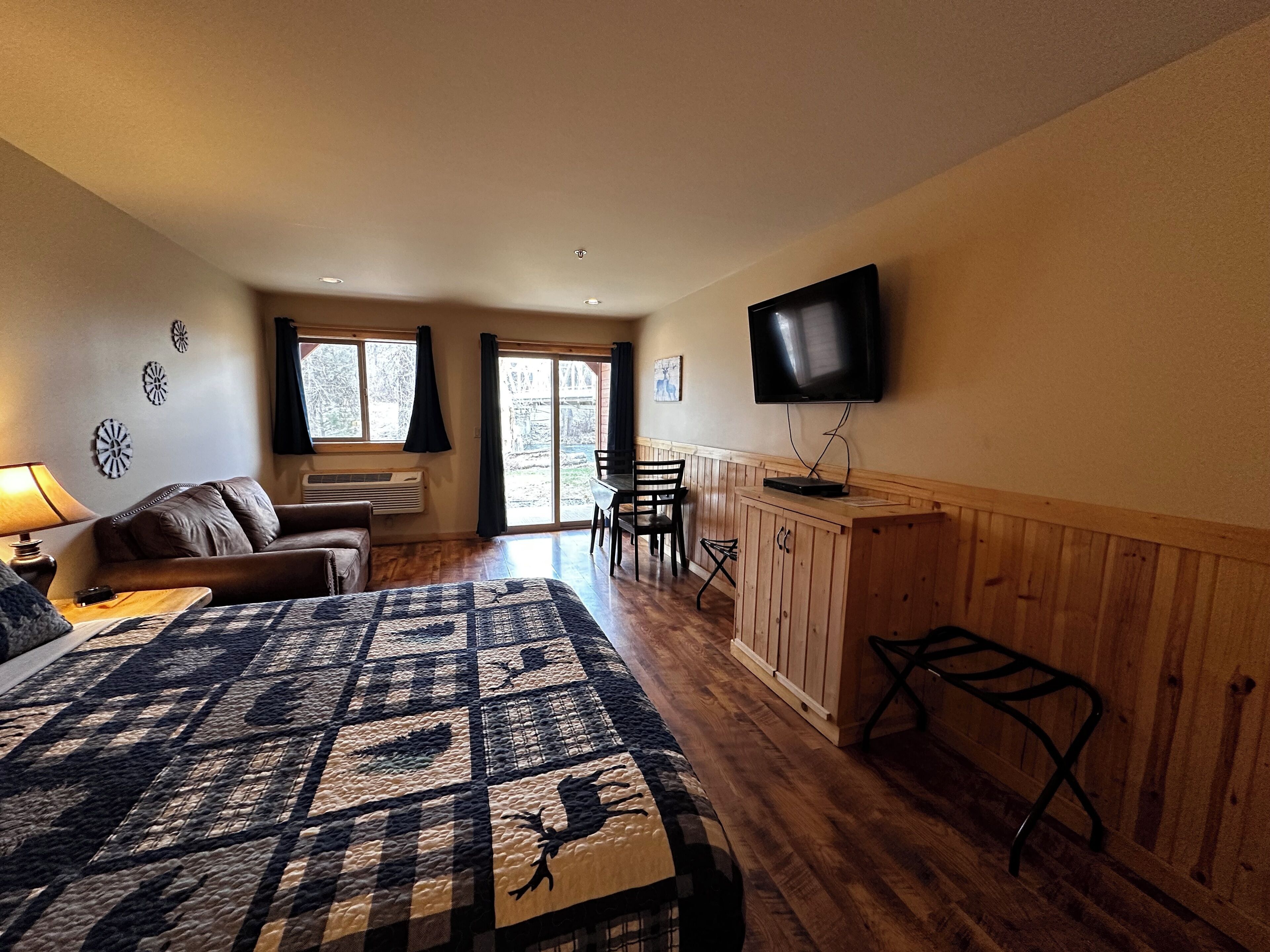 Een slaapkamer met een bed, een aan de muur bevestigde televisie, een bureau en een stoel.