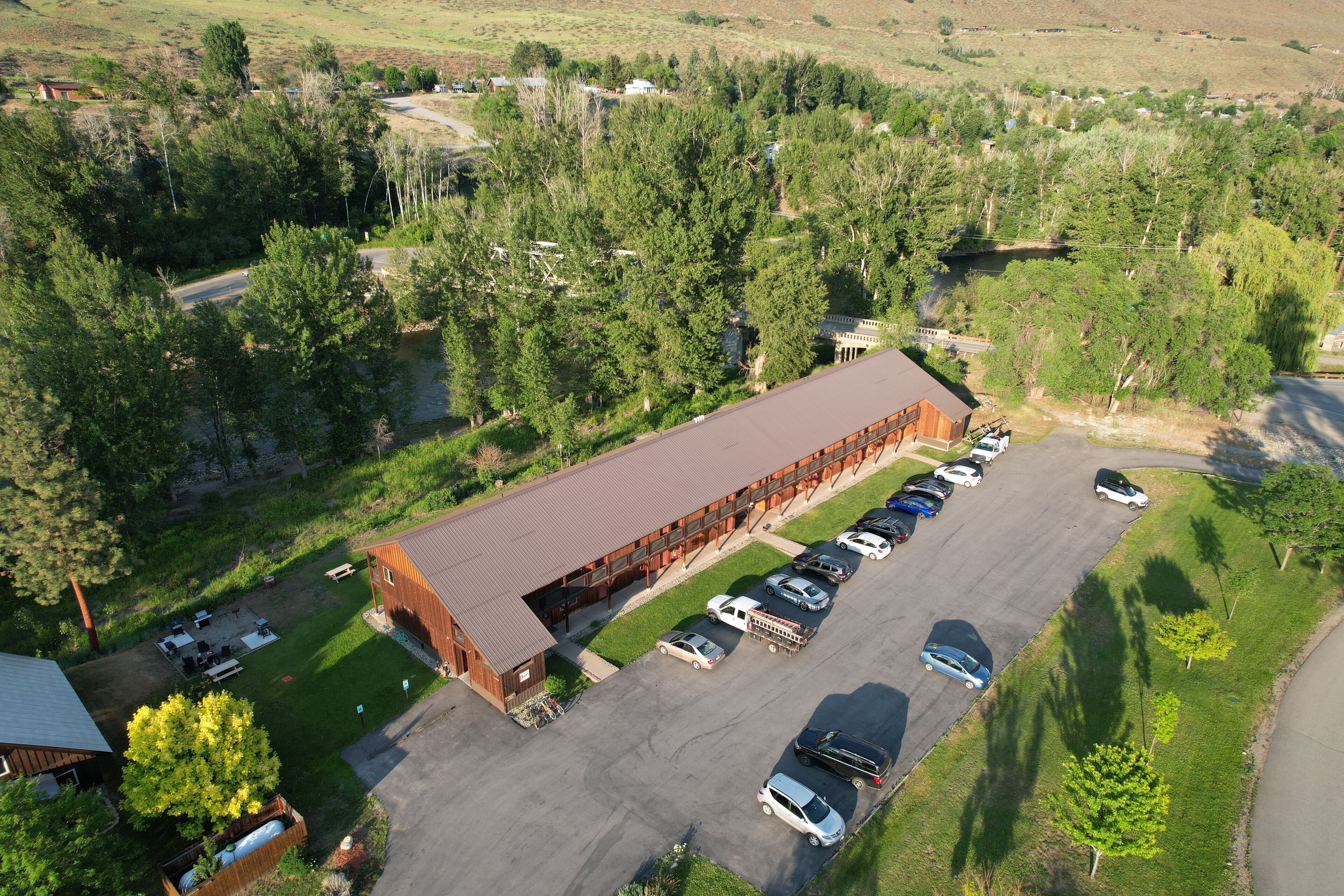 An aerial view of a large building with a parking lot, surrounded by trees and open fields.