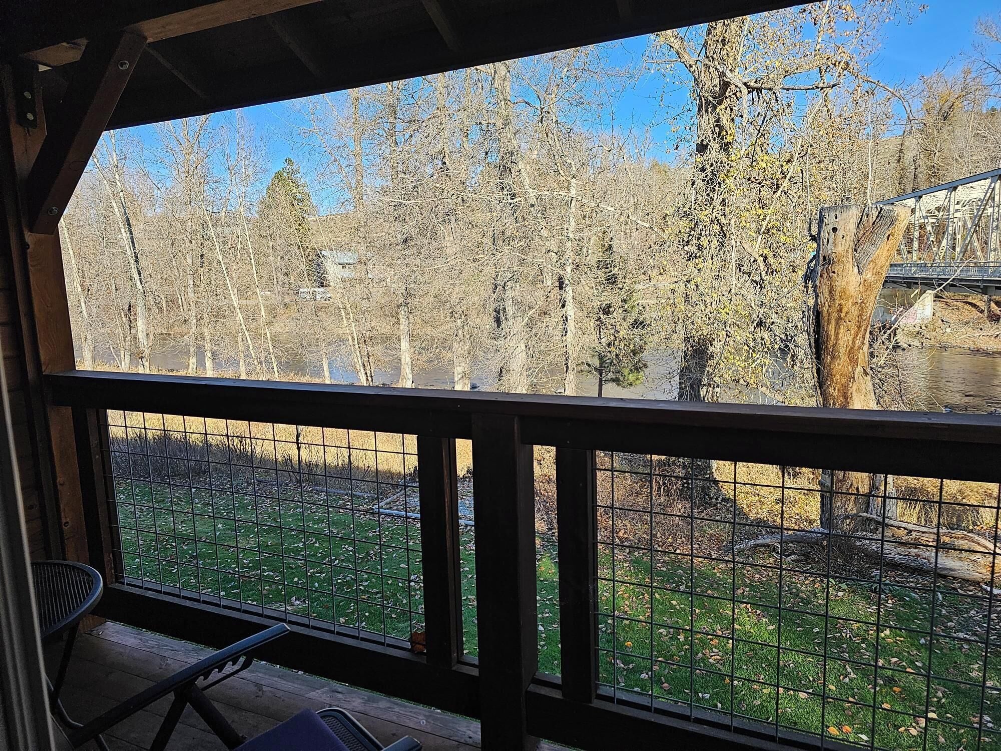 A covered outdoor area with a view of a fenced yard and trees.