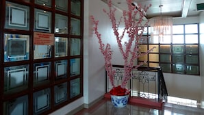 A hotel lobby with a large window display, a decorative vase with pink flowers, and a sign indicating the establishment is non-smoking. - Orange Grove Hotel (Davao)