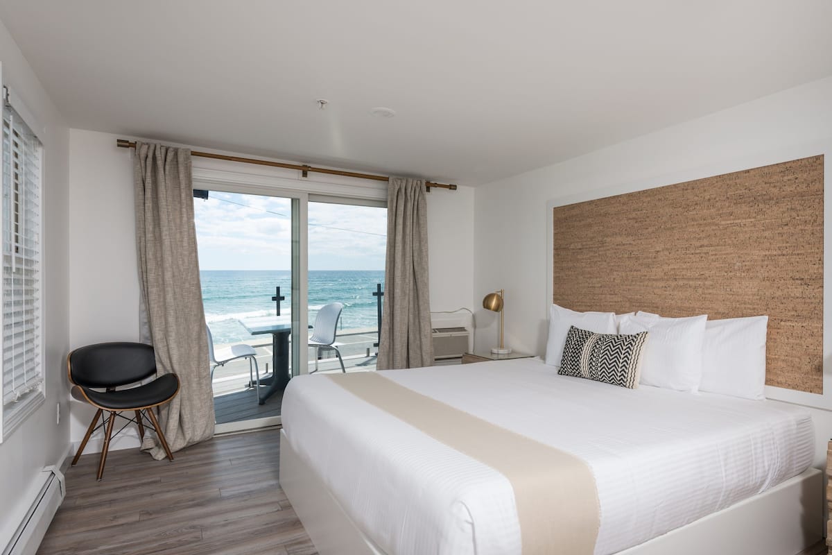 A hotel room with a large bed, a desk, and a view of the ocean.