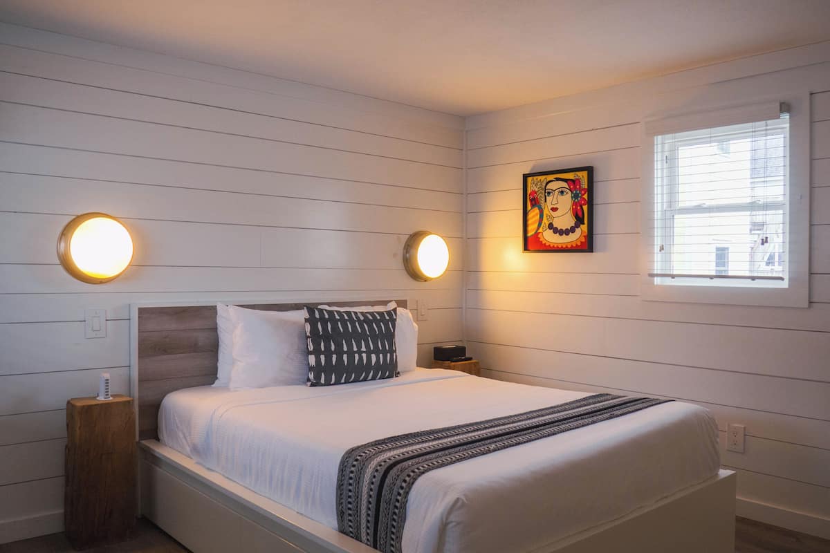 A neatly arranged bedroom with a bed, two bedside tables, and a wall-mounted light fixture.