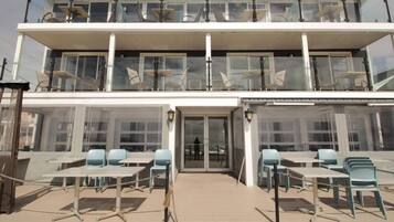 A two-story building with a balcony on the upper floor and a covered outdoor seating area with tables and chairs.