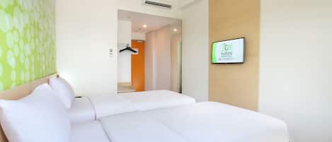 A hotel room with a bed, a wall-mounted TV, and a door leading to a bathroom.