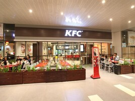 A KFC restaurant with outdoor seating and a modern ceiling design.