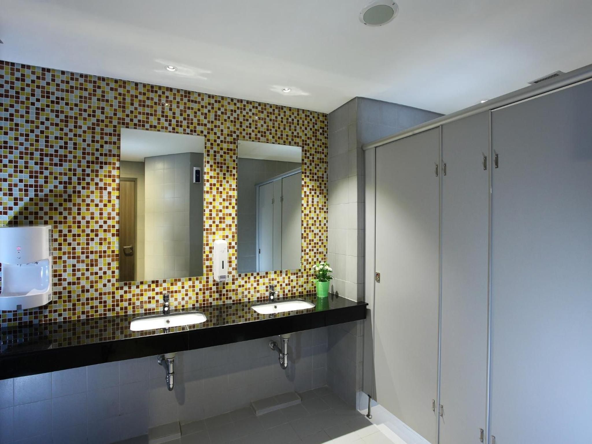 A modern bathroom with two sinks, a large mirror, and a toilet.