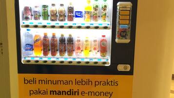 Een automaat met een bord waarop staat 'e-money' en 'betaal drankjes gemakkelijker met Mandiri e-money'.