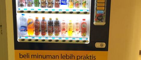 Een automaat met een bord waarop staat 'e-money' en 'betaal drankjes gemakkelijker met Mandiri e-money'.