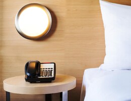 Ein Hotelzimmer mit Nachttisch, Telefon und Wandleuchte.
