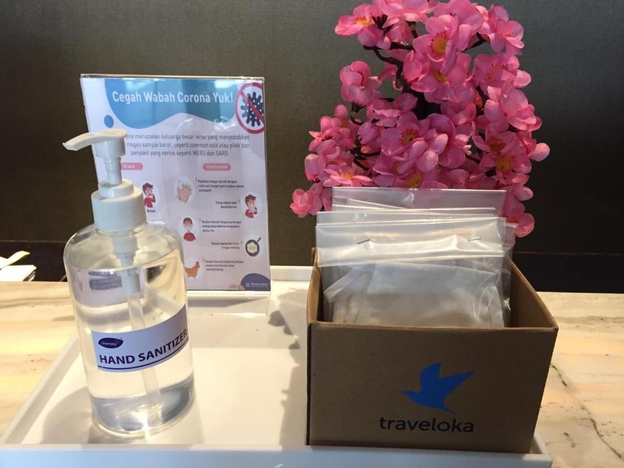 Una botella de gel hidroalcohólico, una caja con una flecha azul y un cartel sobre coronavirus.