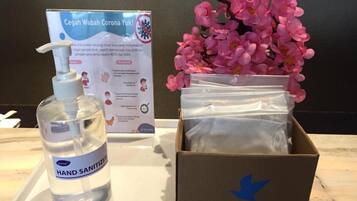 Una botella de gel hidroalcohólico, una caja con una flecha azul y un cartel sobre coronavirus.