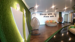 A modern interior with a green wall, a hanging light fixture, and a sign offering free wifi. - Ton Koon Hotel (Udon Thani)