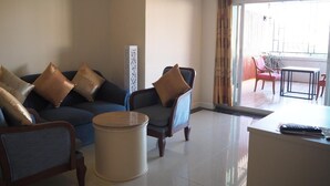 A modern living room with a sofa, armchairs, a coffee table, and a dining area with chairs and a table. - Ton Koon Hotel (Udon Thani)