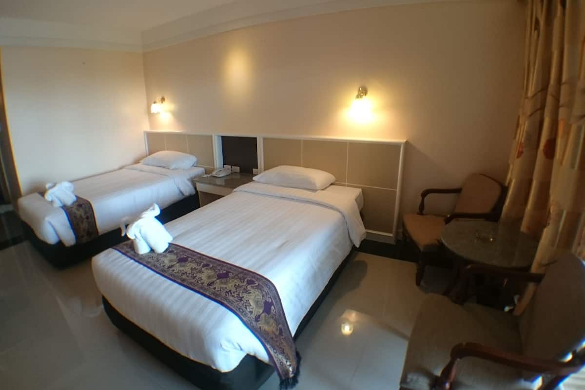A hotel room with two beds, a small table, a chair, and a nightstand with a phone.
