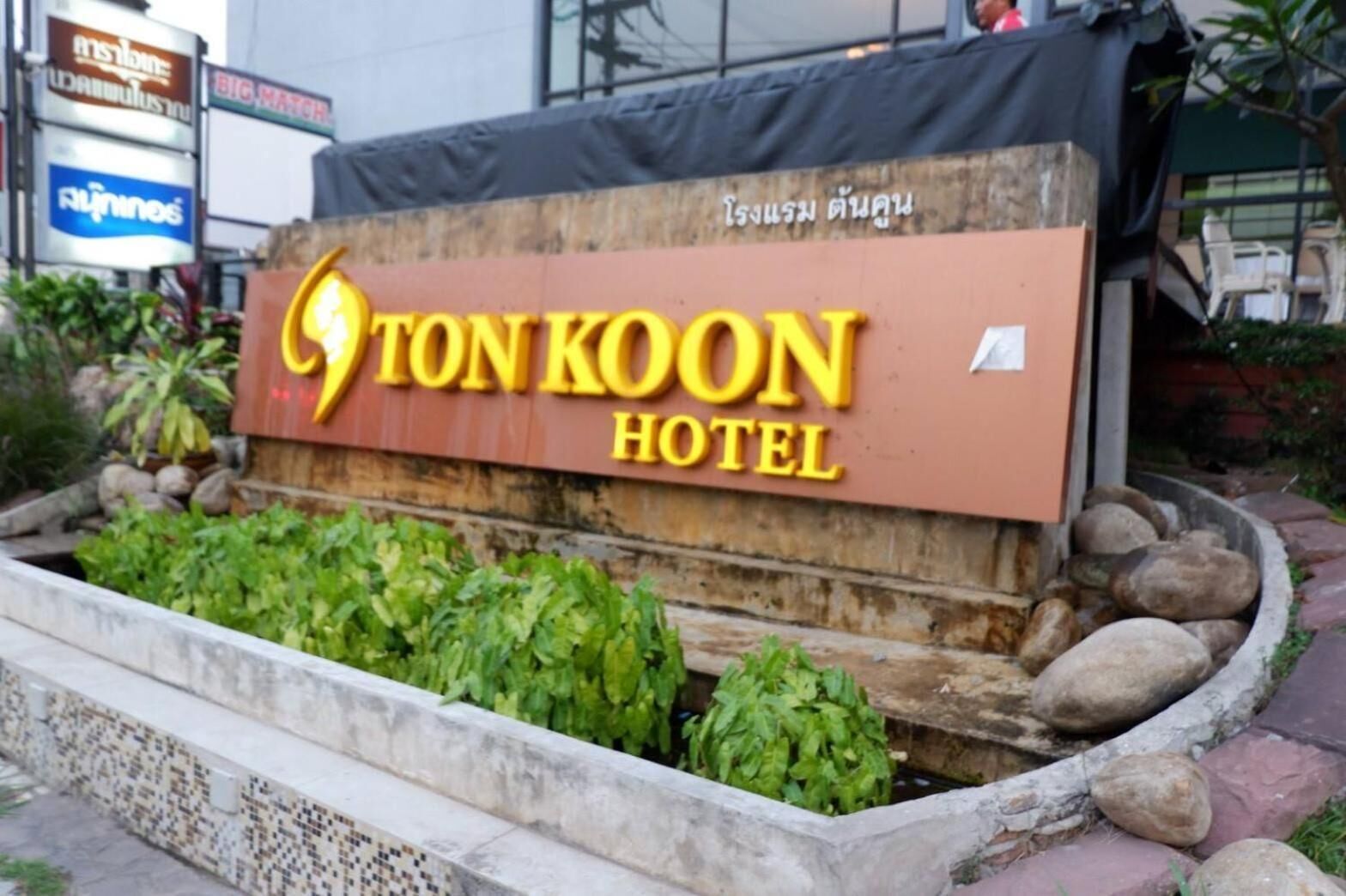 Schild für das TonKoon Hotel mit Logo und Schriftzug in Gelb auf Holz.