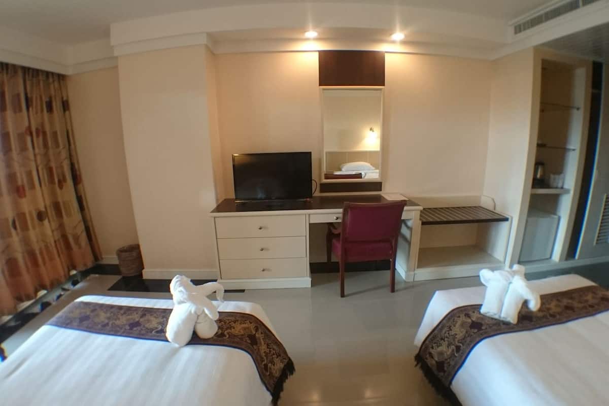A hotel room with two beds, a desk with a television, a chair, and a mirror.