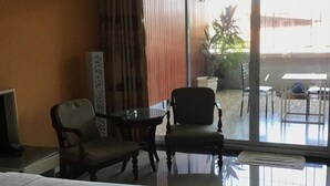 A hotel room with a bed, two armchairs, a small table, and a TV. - Ton Koon Hotel (Udon Thani)