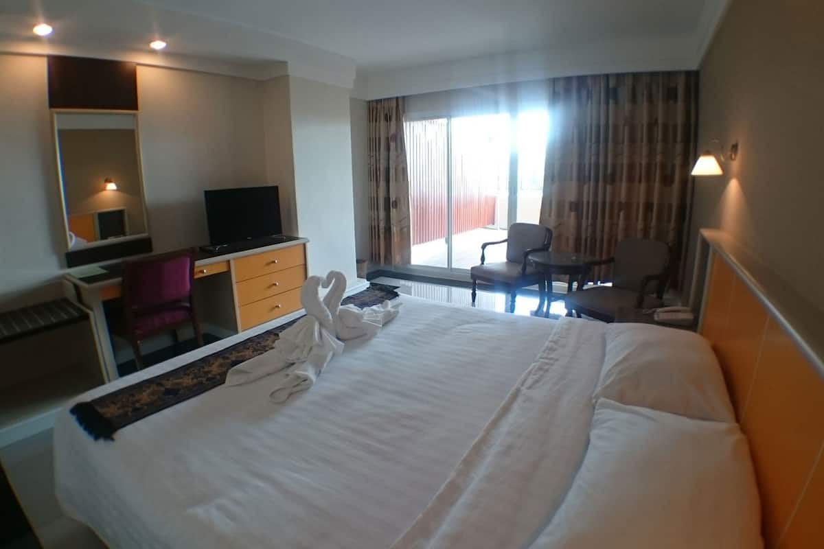 A hotel room with a bed, a desk, a chair, a television, and a large window with curtains.