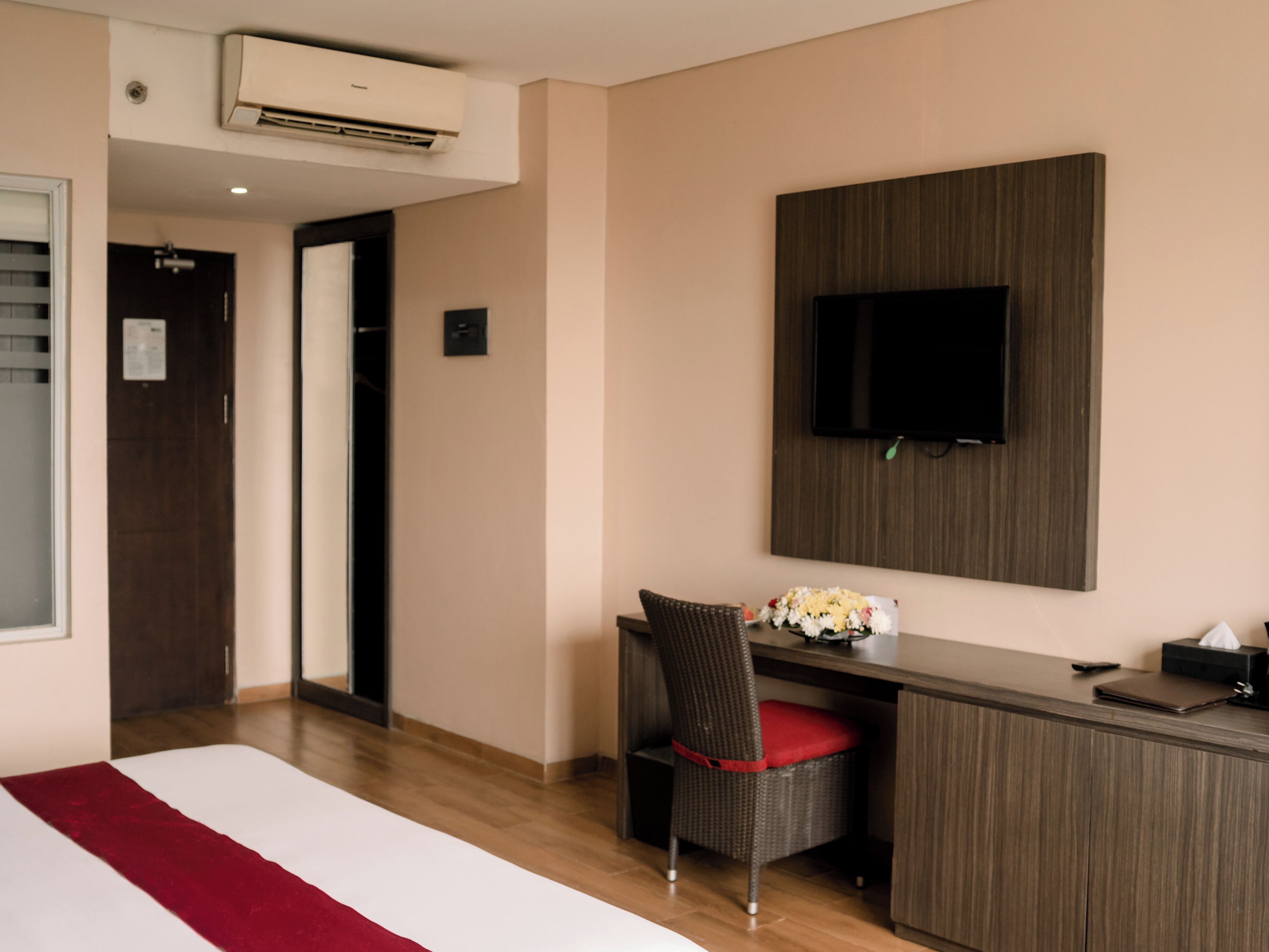 Habitación de hotel con cama, escritorio, silla, televisión y aire acondicionado.