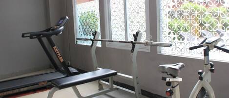 Une salle de sport équipée d’un tapis de course, d’un banc de musculation et d’un vélo d’appartement.