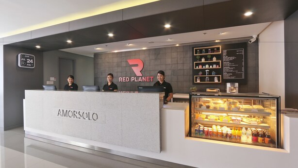 A Red Planet branded reception desk with a glass display case of beverages. - Red Planet Makati Amorsolo (Makati)
