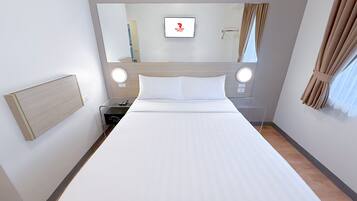 A hotel room with a large bed, a bedside table with a lamp, a mirror, and a wall-mounted TV.