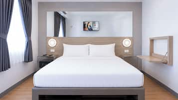 Una camera d'albergo moderna con un letto grande, comodini, una TV a parete e una mensola in legno.
