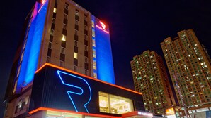 A modern hotel with a prominent 'R' logo, multiple floors, and illuminated signage. - Red Planet Makati Amorsolo (Makati)